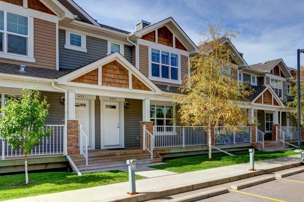 Row of brown-and-white townhouses with front porches and a tree-lined street