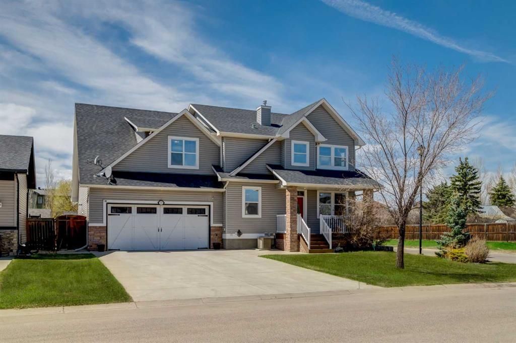 Suburban two-story house with a garage, driveway, and small front porch under a blue sky