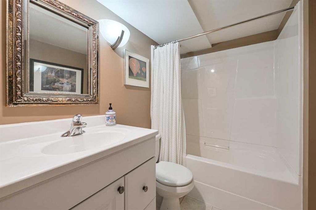 Bright bathroom with vanity, mirror, sink, and bathtub with shower curtain