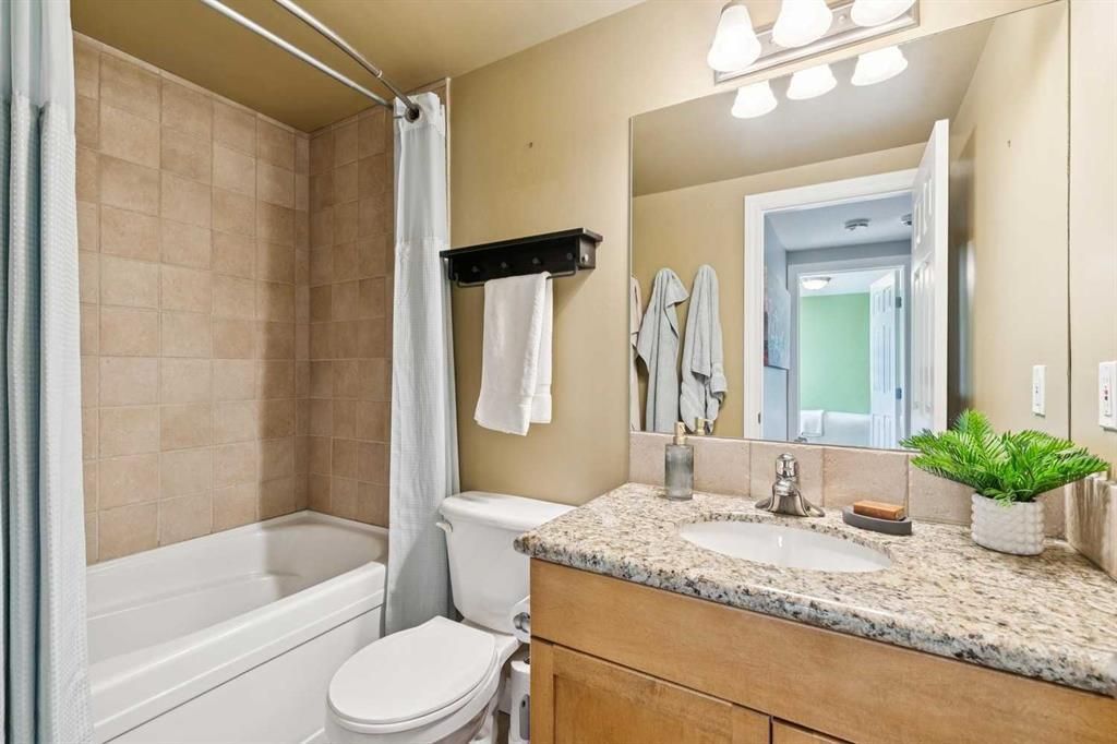 Modern bathroom with bathtub, granite vanity, mirror, and beige tile walls.
