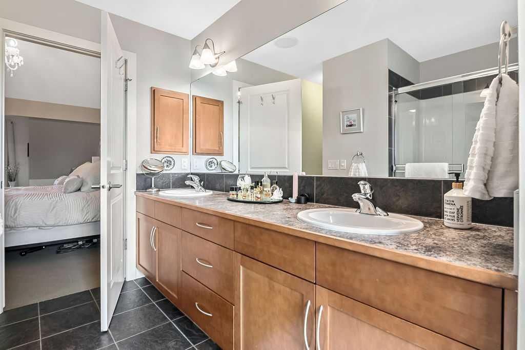 Spacious bathroom with double vanity, large mirror, and dark tile floor in soft gray tones