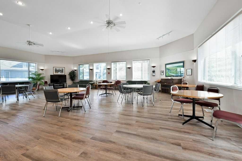 Spacious modern dining hall with tables, chairs, wood floors, and large windows with natural light