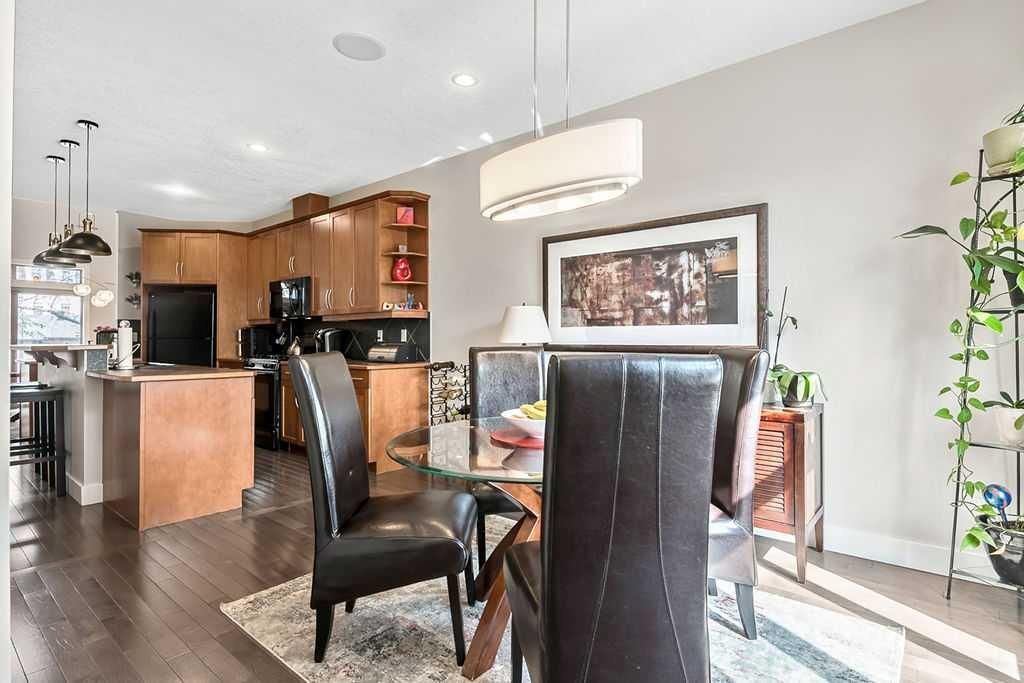 Modern dining area with black chairs, glass table, and open kitchen in the background