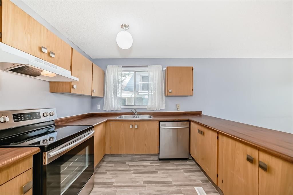 Modern kitchen with wood cabinets, stainless appliances, and a window over the sink