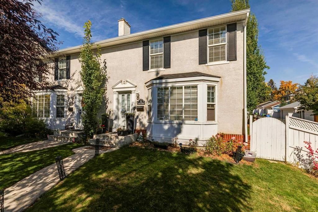 Two-story white house with a front garden and bay window, viewed on a sunny day