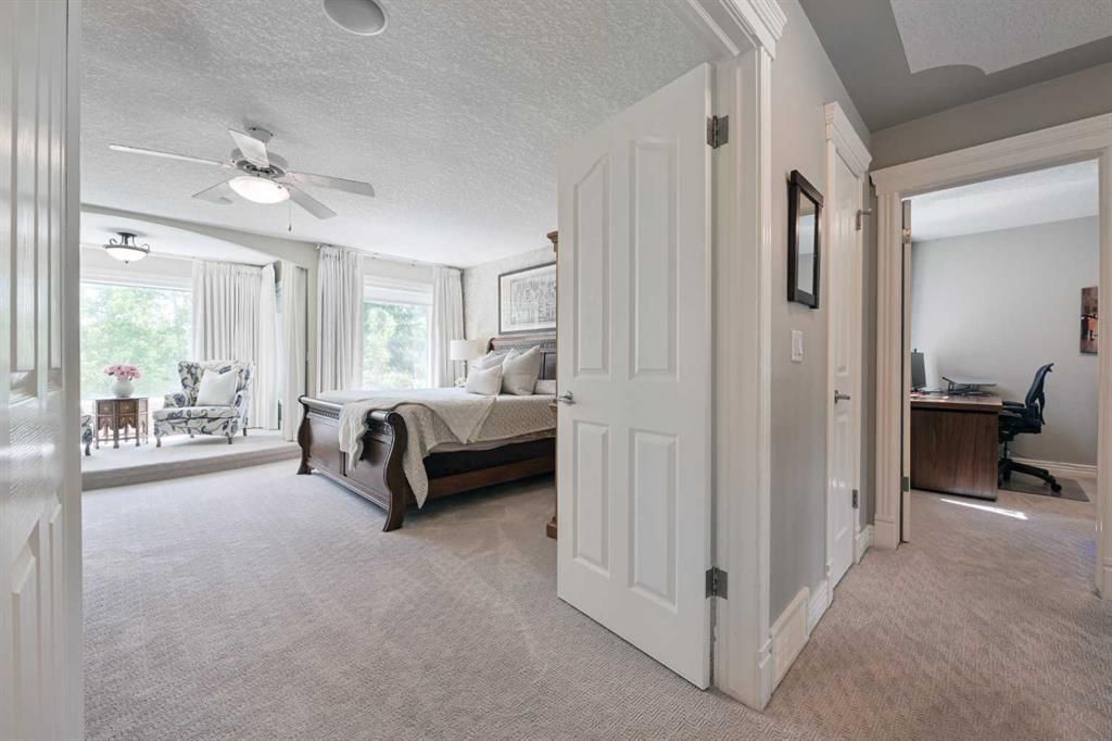 Bright bedroom with carpet, bed, and adjacent sitting area near large windows