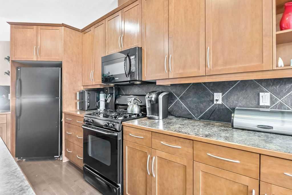Modern kitchen with wood cabinets, black appliances, and granite countertops