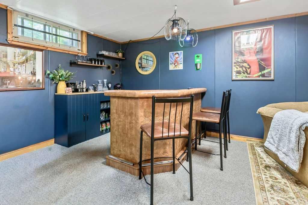 Blue basement lounge with bar, stools, framed art, and a pool table edge.