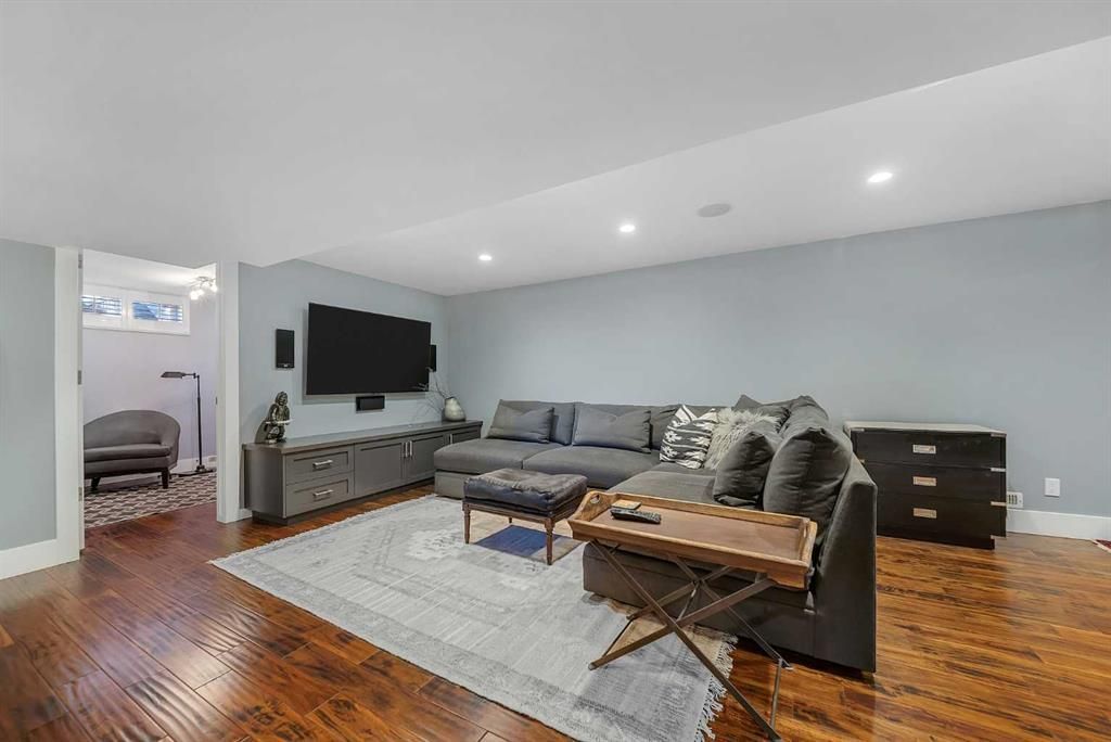 Modern living room with gray sofa, TV, wooden coffee table, and hardwood floors