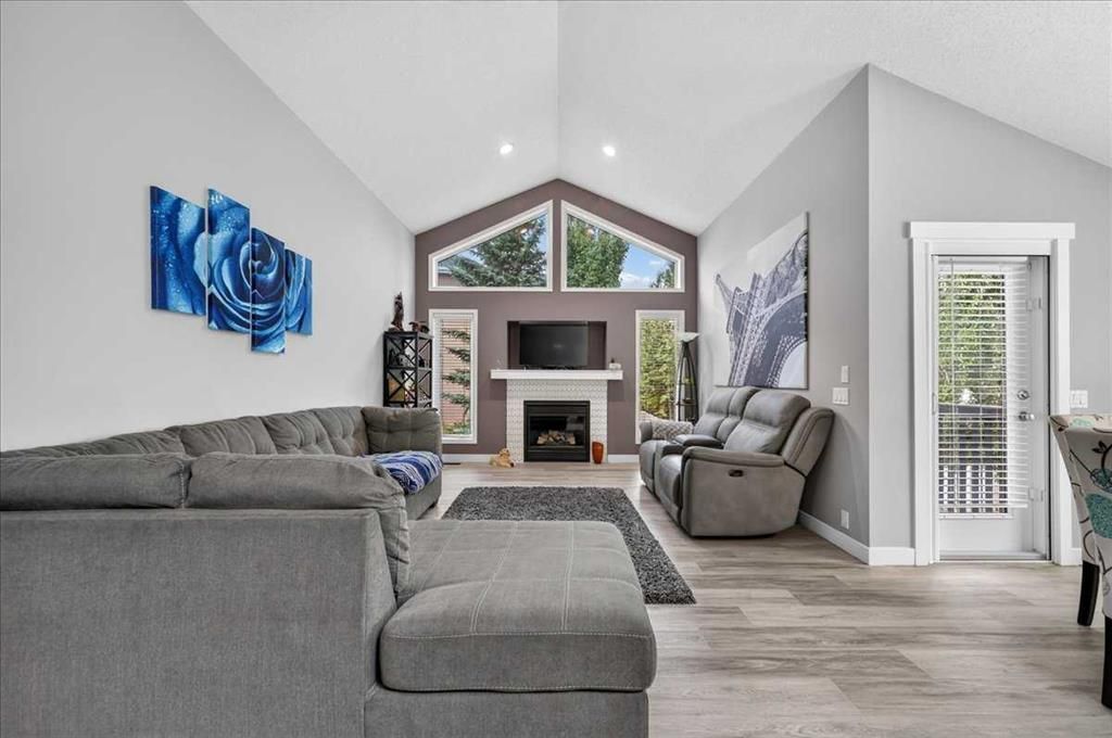 Modern living room with gray sectional, fireplace, vaulted ceiling, and large windows