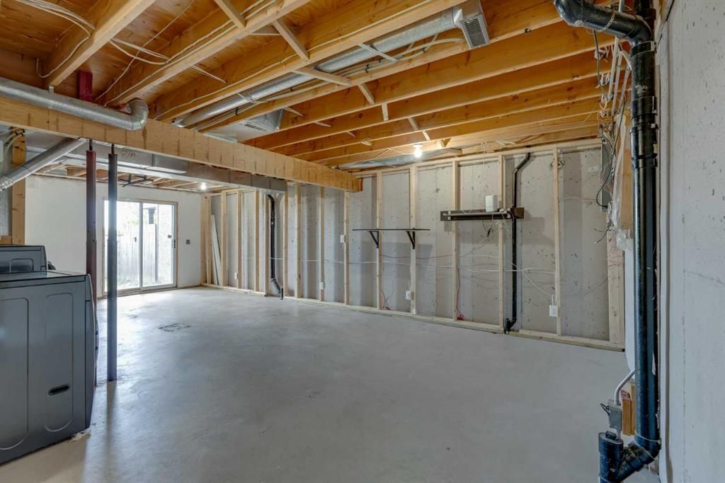 Unfinished basement interior with exposed wood beams, insulation, and concrete floor