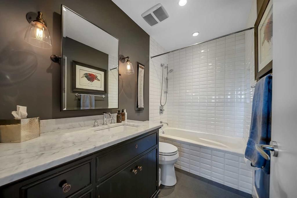 Modern bathroom with black vanity, white tile shower, and bathtub with a glass shower curtain