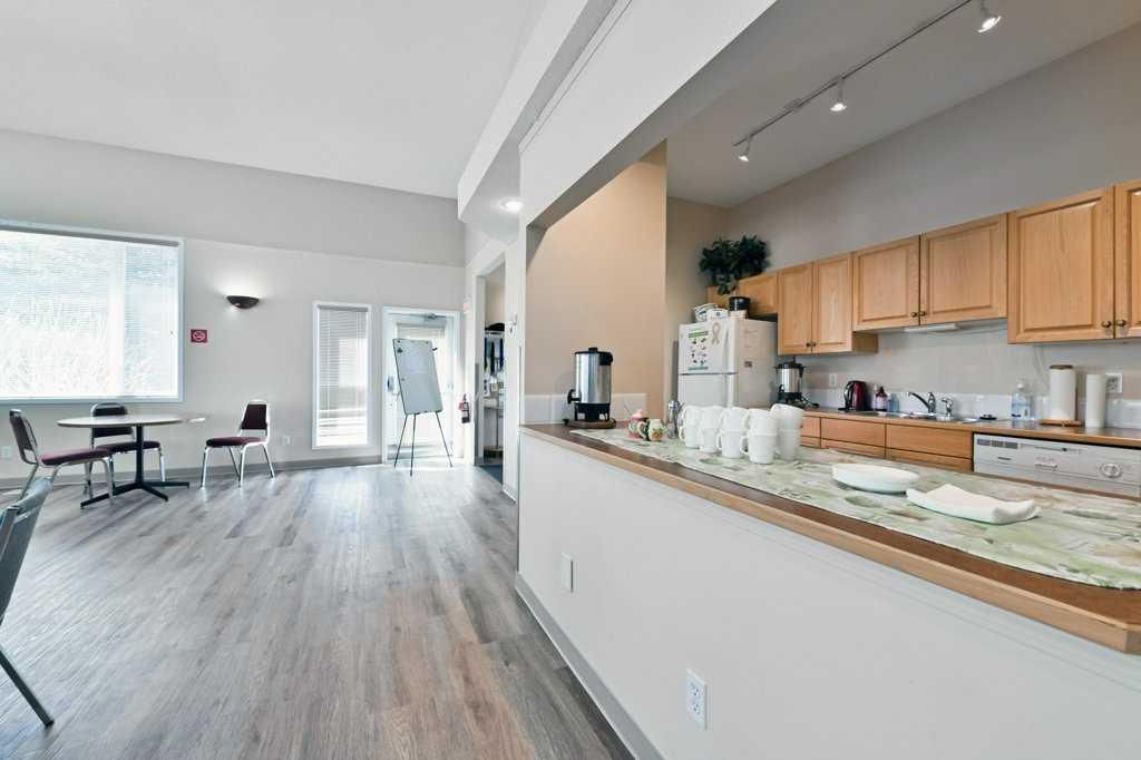 Open kitchen and dining area with light wood cabinets, gray flooring, and large bright windows
