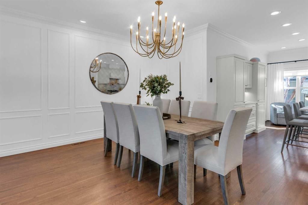 Bright dining room with a wood table, gray chairs, chandelier, and hardwood floors