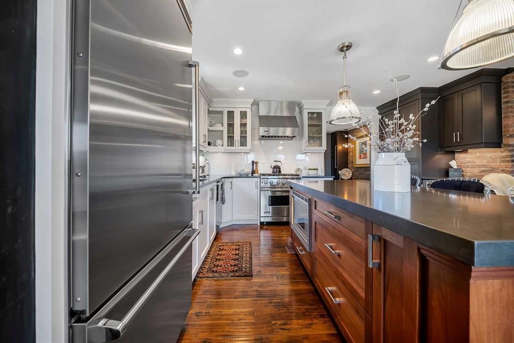 Modern kitchen with stainless steel appliances, dark island, white cabinets, and wood floors