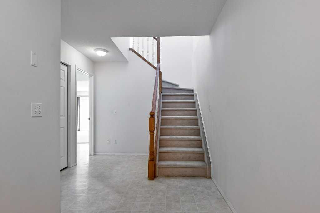 Empty hallway with carpeted staircase, white walls, and a wooden handrail