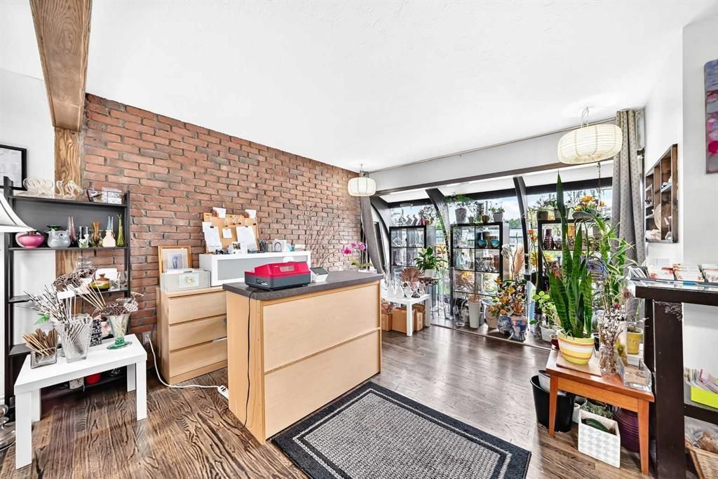 Bright art studio with brick wall, large windows, potted plants, and a central work table
