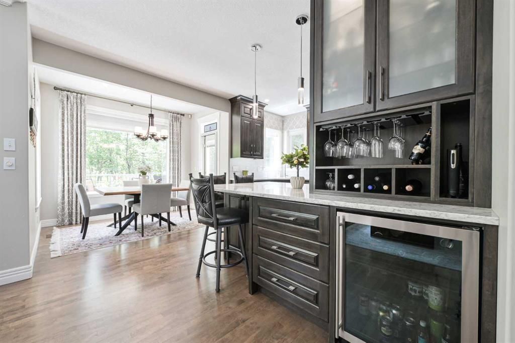 Modern open-concept kitchen and dining area with wood floors, bar stools, and sliding glass doors to a bright patio.