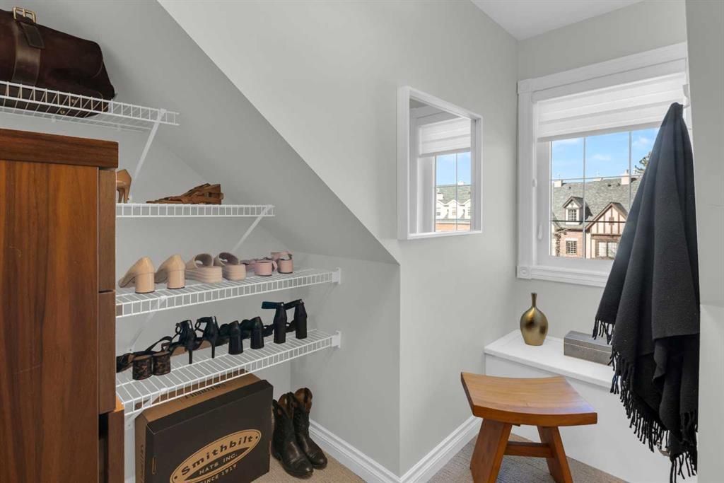 Small white entryway with shoe shelves, bench, hooks, and a window by a lake-view.
