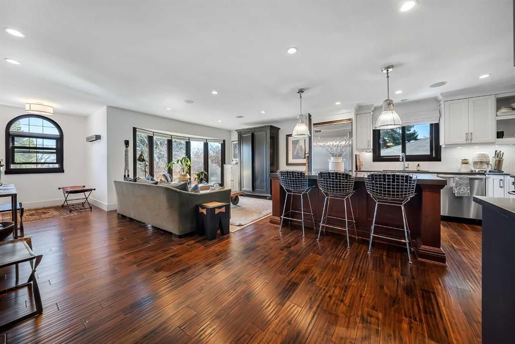 Bright open-concept kitchen and living room with hardwood floors, gray sofa, and large windows