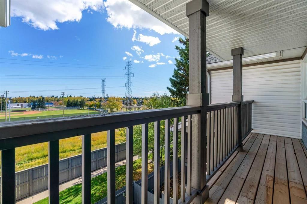 Covered wooden porch overlooking a grassy field and blue sky