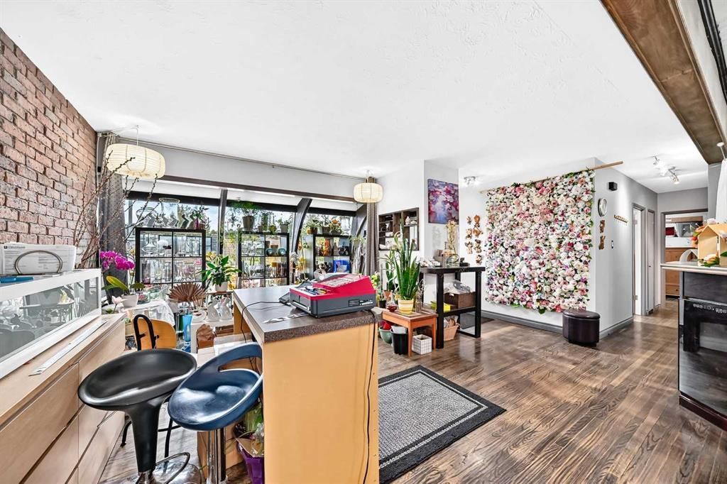 Bright open-plan kitchen and living space with wood floors, bar stools, and floral accent wall