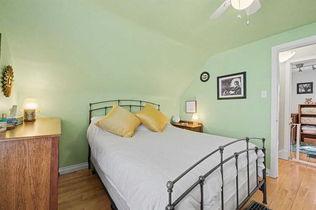 Light green bedroom with a black metal bed, yellow pillows, and open doorway to a dining room.