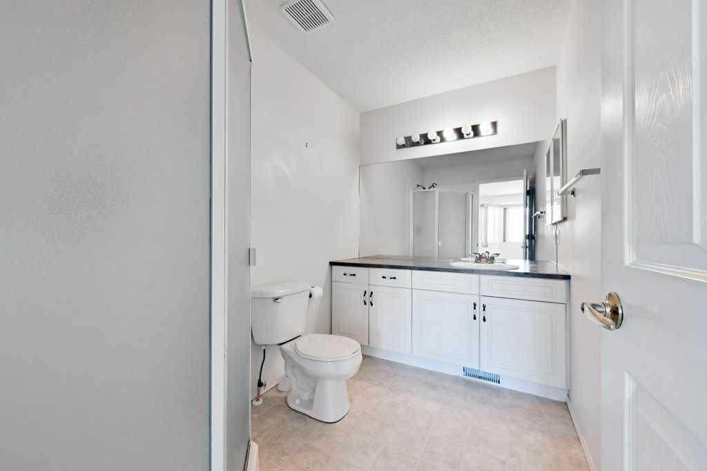 Bright white bathroom with toilet, vanity sink, mirror, and open door