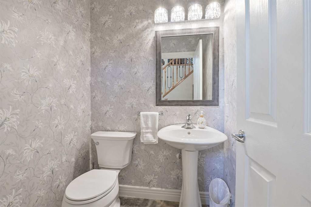 Small white bathroom with toilet, pedestal sink, mirror, and tiled floor