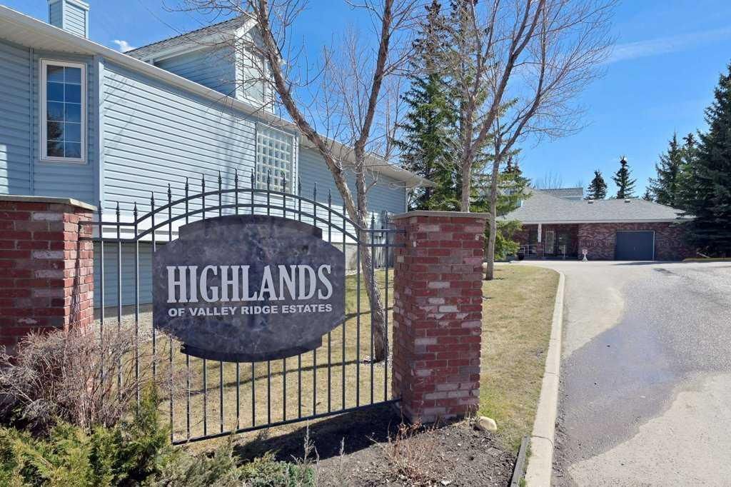 Entrance sign for Highlands at Valley View, with brick pillars, black gate, and a driveway beside homes
