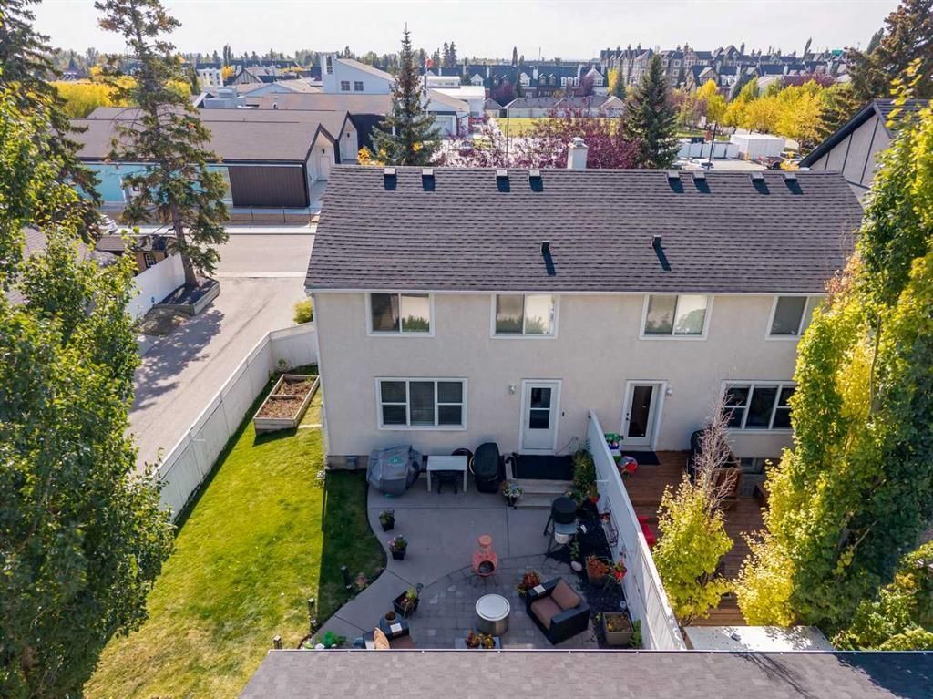 Aerial view of a white house with a patio, lawn, and trees in a suburban neighborhood.