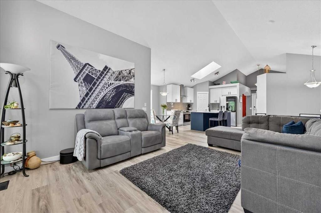 Bright open living room with gray sofa, blue accent chairs, shag rug, and large wall art