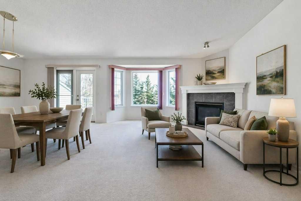 Bright living and dining room with beige furniture, fireplace, and large windows