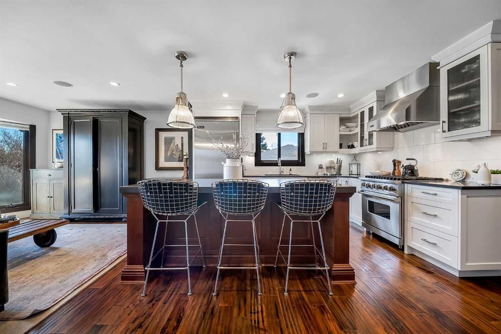 Modern kitchen with dark wood island, white cabinets, pendant lights, and hardwood floors