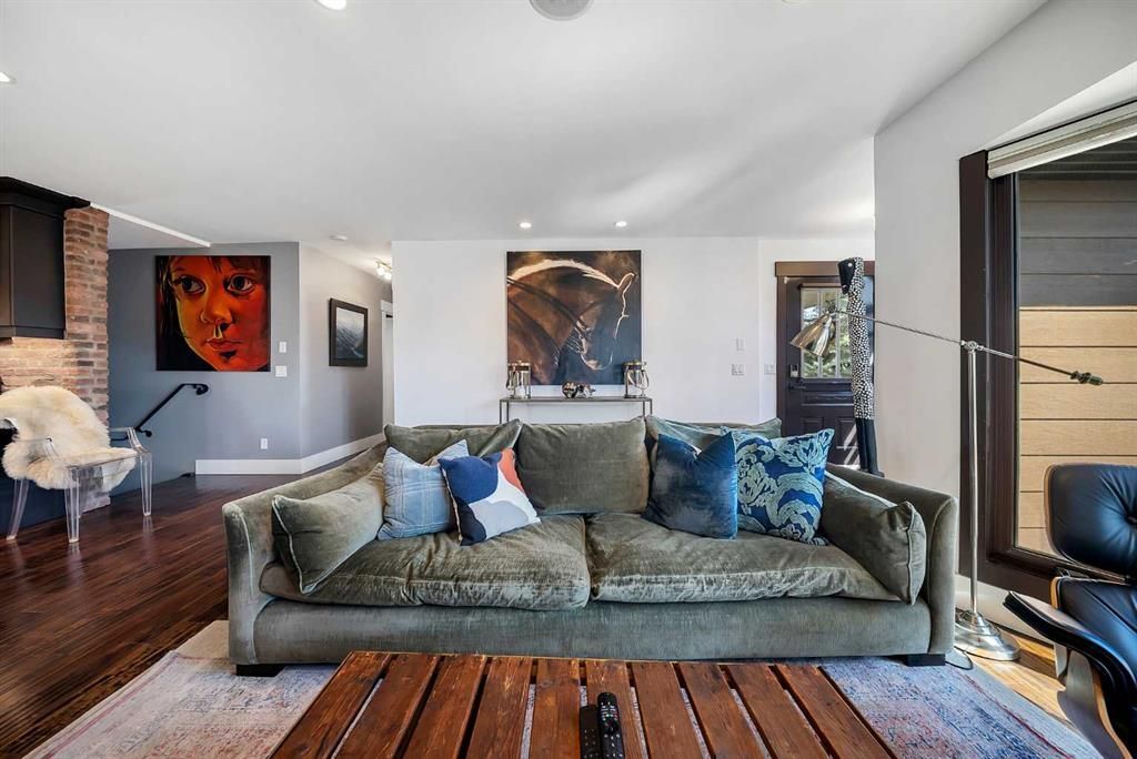 Modern living room with gray sofa, abstract art, wood floor, and large windows with city view