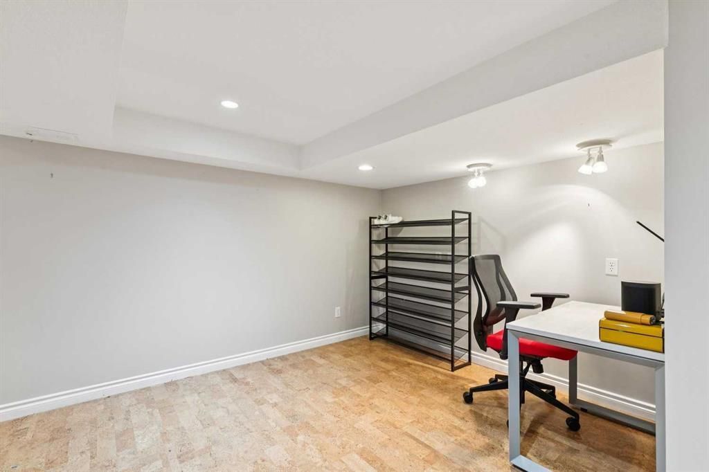 Empty home gym or workshop with metal rack, treadmill, and workbench on wood floor.