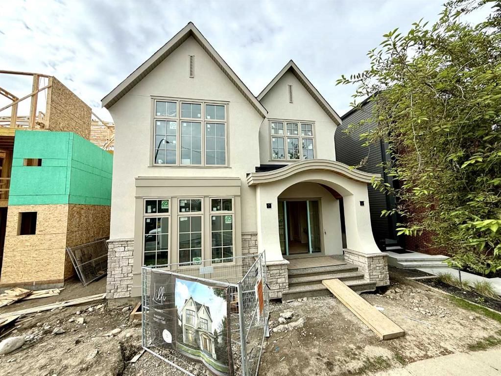 Two-story house under construction with gray siding, front porch, and unfinished yard