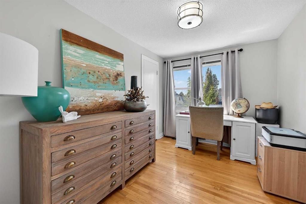 Bright bedroom with wooden dresser, desk by window, and coastal wall art