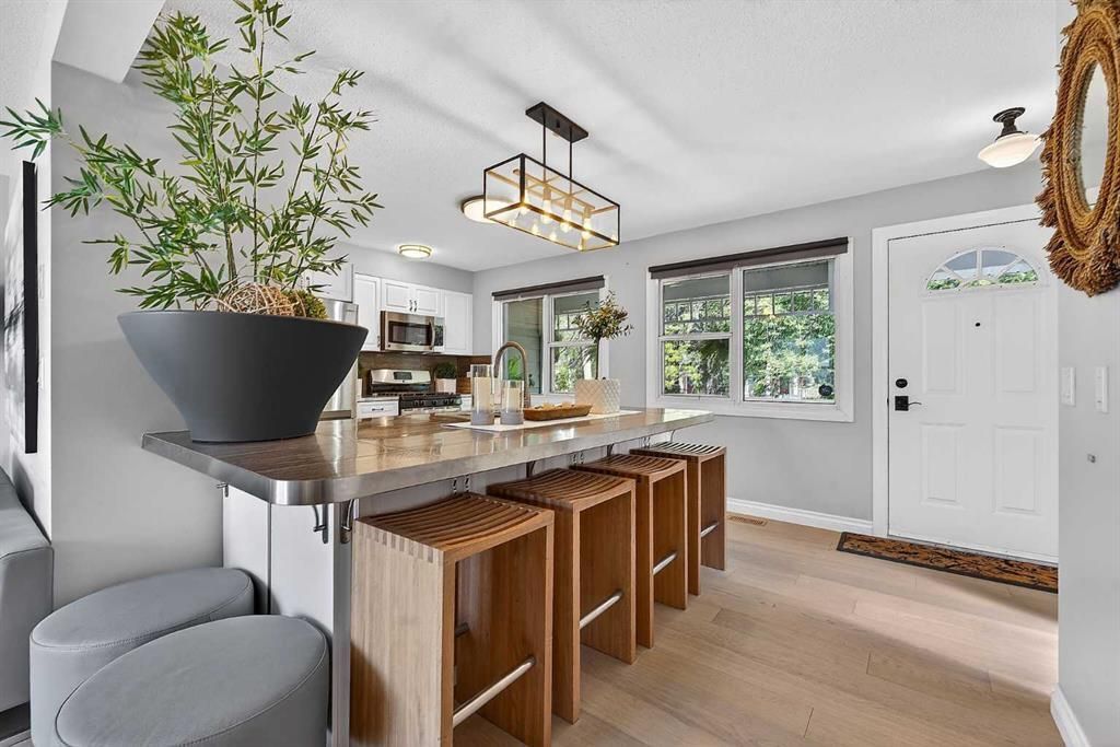 Bright modern kitchen with island seating, pendant lights, large windows, and a potted plant