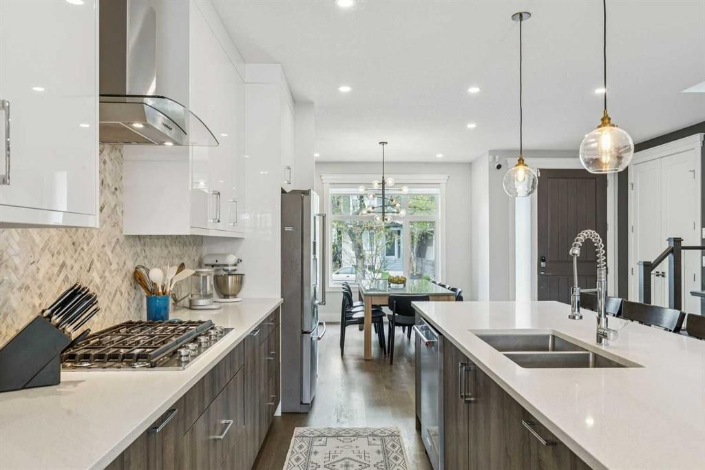 Bright modern kitchen with white cabinets, stainless appliances, and a large island with sink and pendant lights