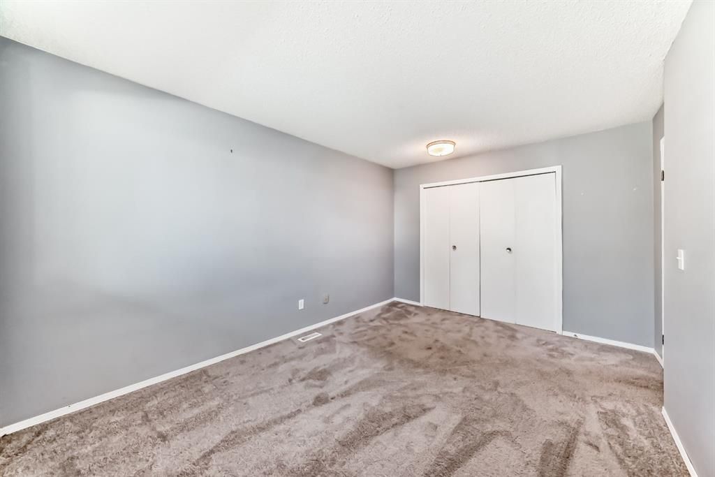 Empty gray bedroom with carpeted floor and white closet doors