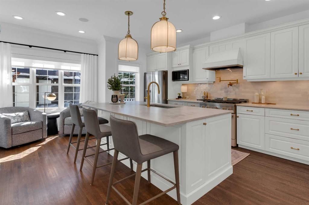 Bright modern kitchen with white cabinets, island seating, pendant lights, and a cozy window nook