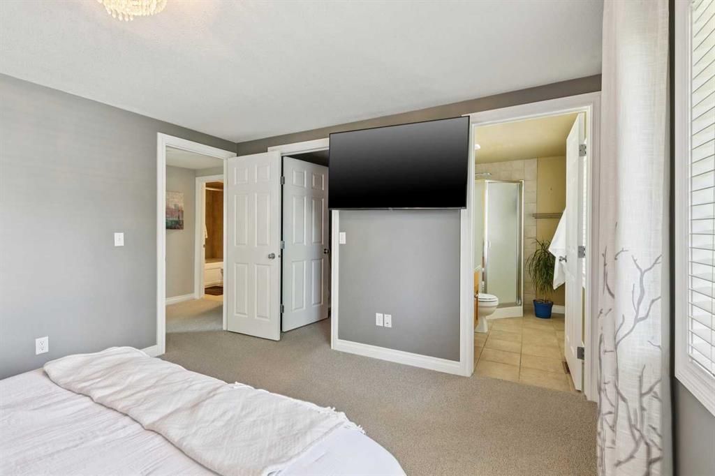Bright bedroom with gray walls, white trim, open closet doors, and a bed in the foreground.