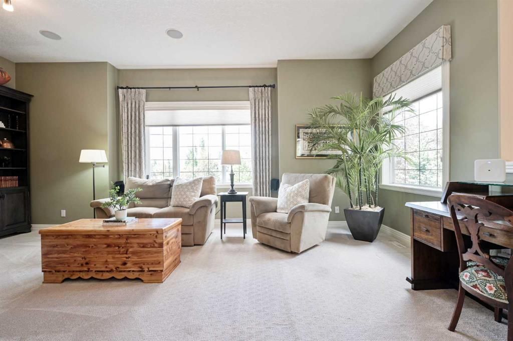 Bright living room with beige furniture, large windows, a wooden coffee table, and a potted plant