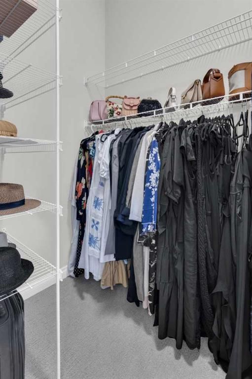 Closet with hanging clothes, hats, and handbags on white wire shelving.