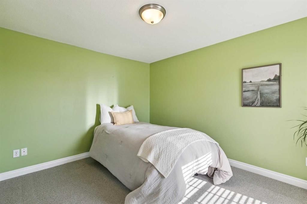Small bedroom with green walls, a single bed, and a framed black-and-white picture.