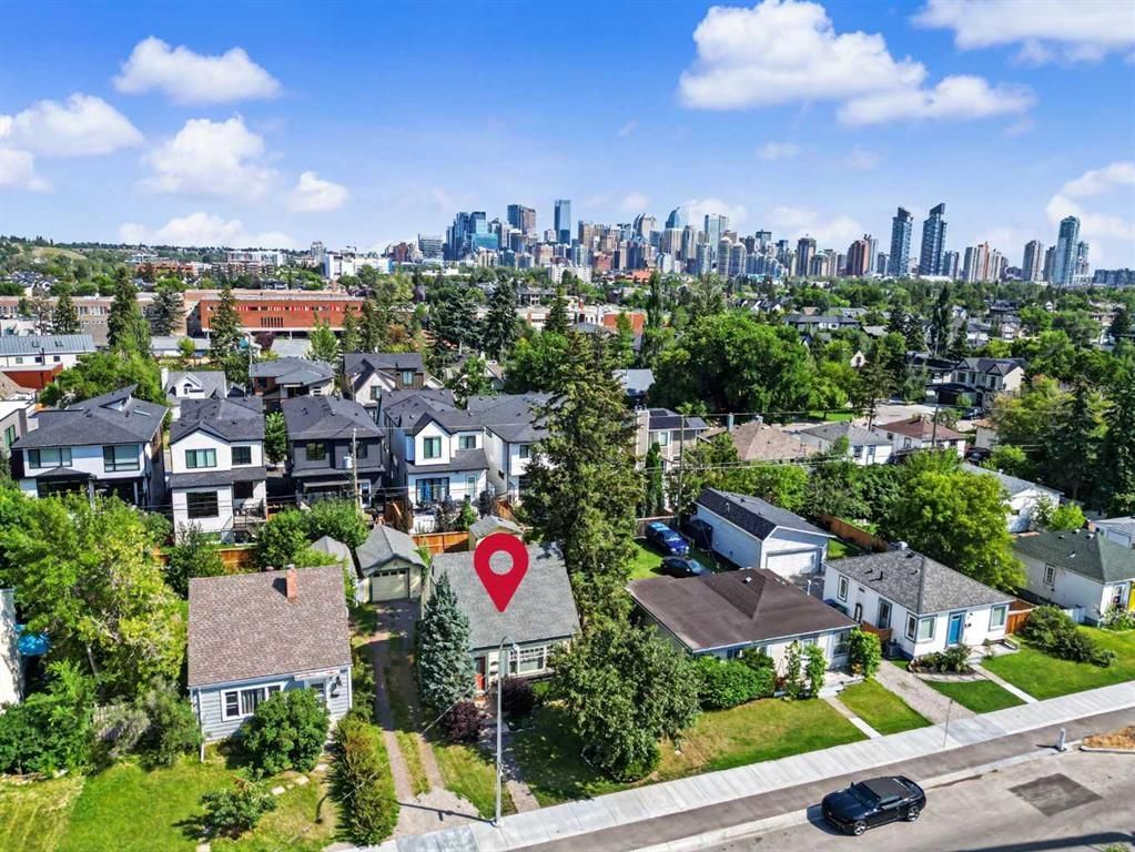 Aerial view of suburban homes with a city skyline in the distance and a red location pin over one house