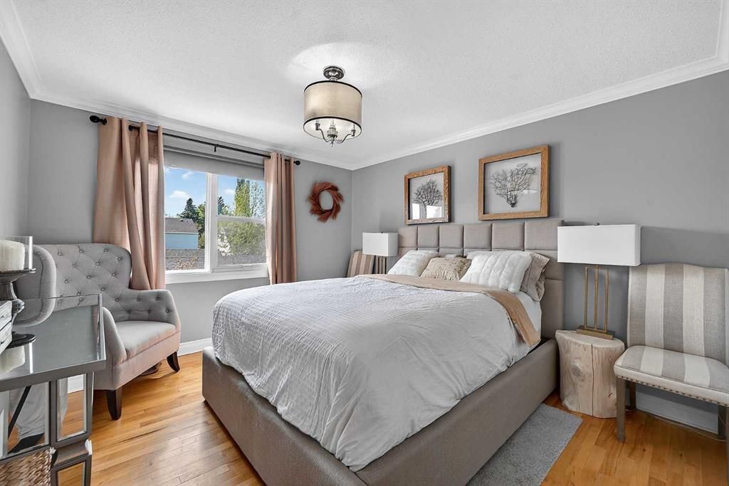 Bright bedroom with a gray bed, striped chairs, and a window with curtains and a wreath