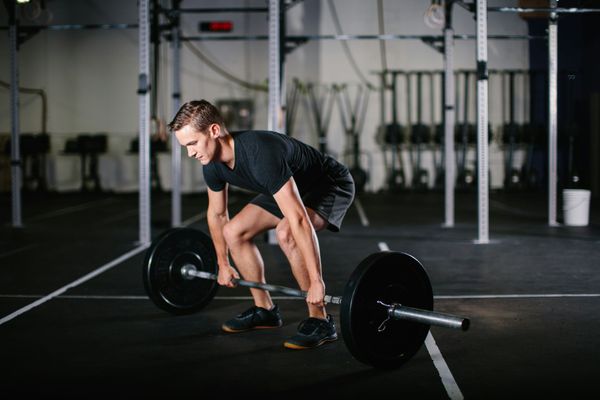 A man is lifting a barbell in a gym.