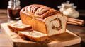 Fresh cinnamon swirl loaf bread on a wooden board with sliced pieces, jars, and cinnamon sticks nearby